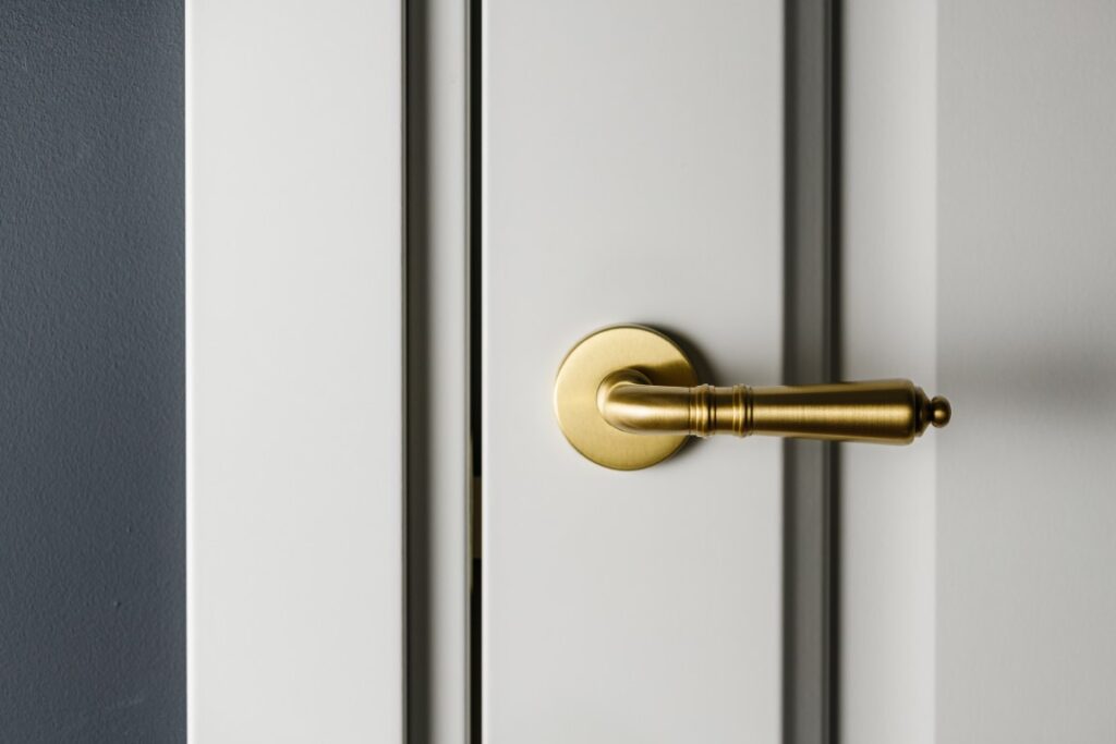 Brushed gold modern design in vintage style door handle on a white door.