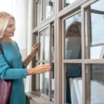 Woman with a burgundy bag standing near a large closet.