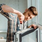 selective focus of concentrated installer holding screwdriver near window